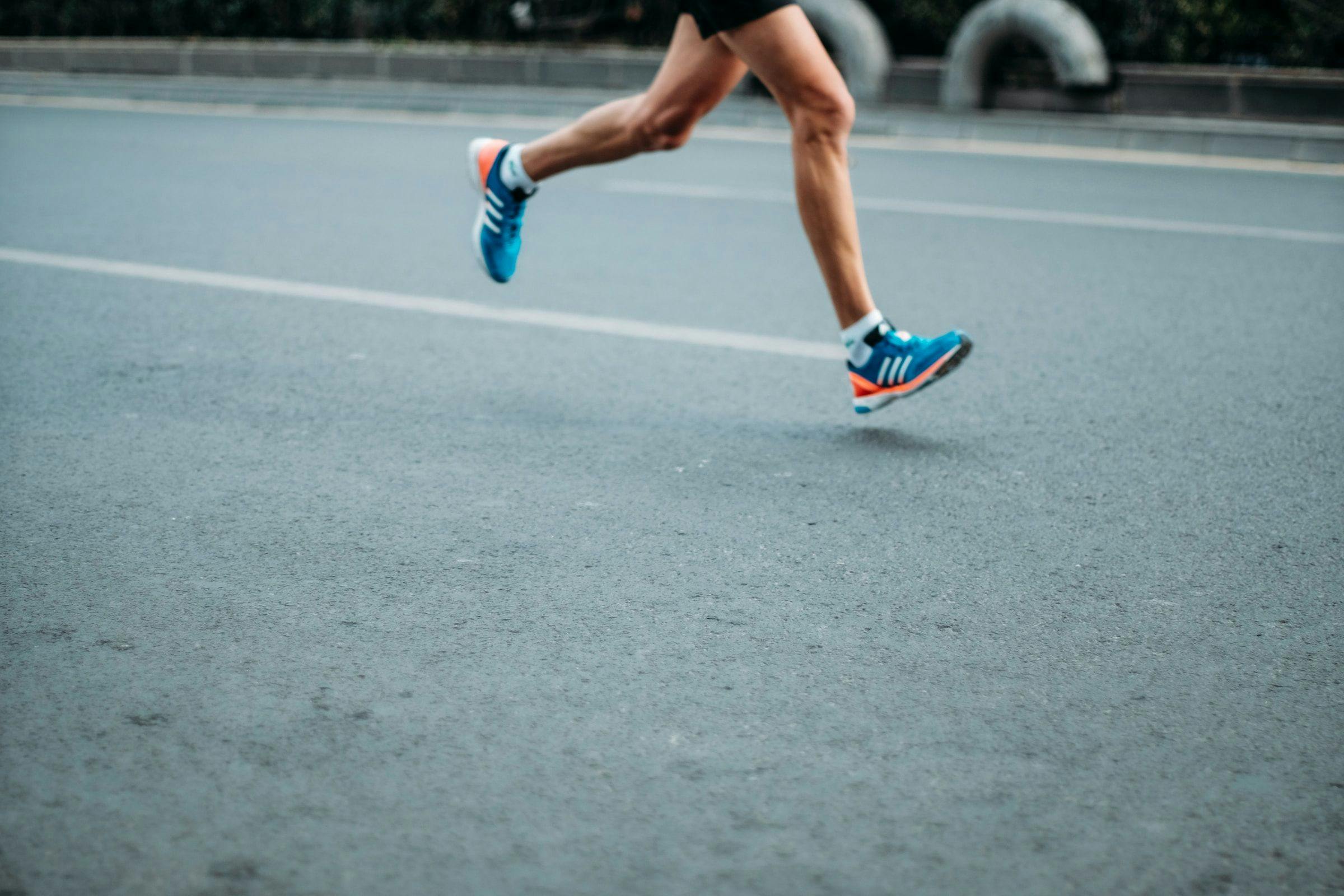 A person in running shoes running on a road.